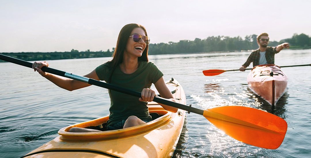 A young woman smiling while kayaking after teeth whitening in Billings.