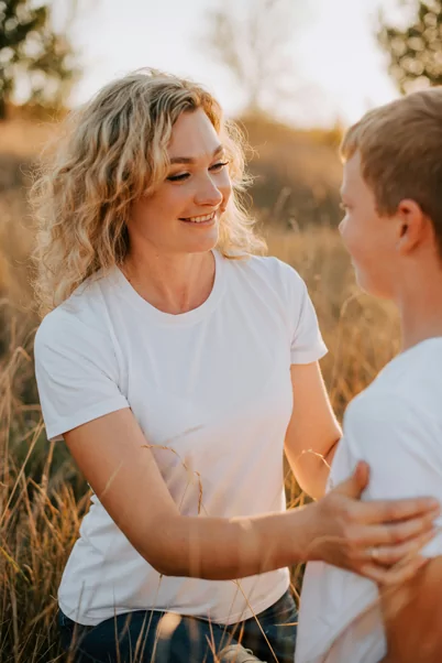Young mother with nice teeth smiles outside playing with her son in Billings, MT