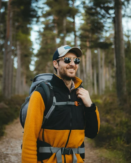 Smiling adult dental fillings patient hiking outdoors with jacket and backpack in Billings, MT