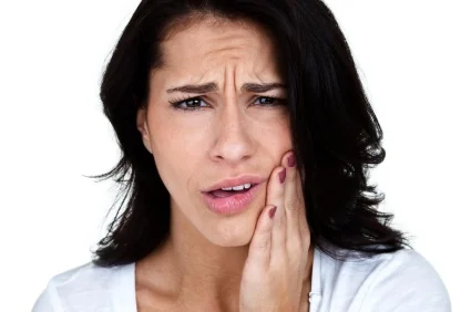 A young woman clutching her jaw from untreated TMJ in Billings.